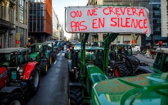 This photograph taken on February 1, 2024, shows rows of tractors, one with a placard reading "We don't die silently", between buildings in the Belliard street  during a protest action in the European district in Brussels, organised by general farmers union ABS (Algemeen Boerensyndicaat) to demand better conditions to grow, produce and maintain a proper income, on the day of a European Council meeting. (Photo by HATIM KAGHAT / Belga / AFP) / Belgium OUT (Photo by HATIM KAGHAT/Belga/AFP via Getty Images)