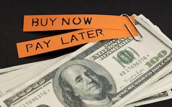BNPL or Buy Now Pay Later concept. Dollar bills and label with message on black background