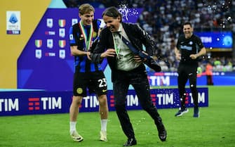 Inter Milan's Italian midfielder #23 Nicolo Barella sprays sparkling wine on Inter Milan's Italian coach Simone Inzaghi during the trophy ceremony for the Italian Champions following the Italian Serie A football match between Inter Milan and Lazio in Milan, on May 19, 2024. Inter celebrates his 20th Scudetto. (Photo by Marco BERTORELLO / AFP) (Photo by MARCO BERTORELLO/AFP via Getty Images)