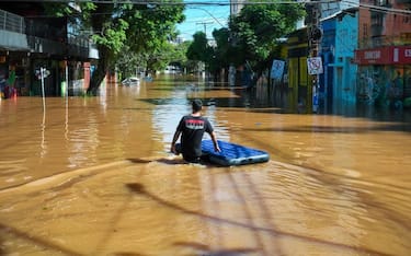 PORTO ALEGRE, BRAZIL - MAY 07: A resident walks through a flooded street with a flotation device as people in the Cidade Baixa neighborhood are evacuated from their homes on May 7, 2024 in Porto Alegre, Brazil. Rescue efforts continue in Porto Alegre due to the floods caused by the heavy rains that have battered Brazilian State of Rio Grande Do Sul. A State of Public Calamity has been called by local government while 281 municipalities have been affected, thousands of people have been displaced and damages in infrastructure cause difficulties to access affected areas or big power outages around the state. (Photo by Jefferson Bernardes/Getty Images)