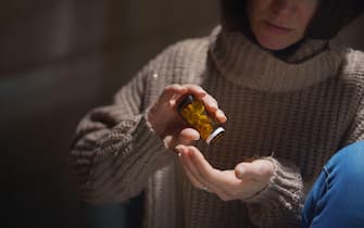 Depressed woman taking pills, mental health concept.