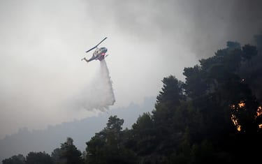 epa10765457 A firefighting helicopter drops water to extinguish a wildfire, in Diakopto, Egio, Greece, 24 July 2023. Firefighting forces along with volunteers in Rhodes, Corfu, Egio, Karystos and Yliki battled flames throughout the night, while airplanes started to operate early in the morning. In Egio, the village of Trapeza was evacuated with a message sent via the emergency number 112 as well as the settlement of Kastro Aegialia, as a fire continues to burn on a nearby hill. A total of 99 firefighters, 35 water trucks and four teams on foot, two aircraft, two helicopters and the Olympos operational centre are operating in the area.  EPA/GIOTA LOTSARI