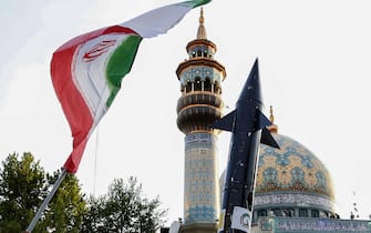 Iranian lift up a flag and the mock up of a missile during a celebration following Iran's missiles and drones attack on Israel, on April 15 2024, at Palestine square in central Tehran. Iran launched the attack on April 14, its first ever to directly target Israeli territory, in retaliation for a deadly air strike widely blamed on Israel that destroyed Tehran's consular building in Syria's capital early this month. (Photo by ATTA KENARE / AFP)
