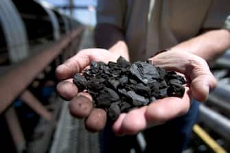 GILLETTE, WY - JUNE 12: A KFx company executive shows off a handful of the company's K-Fuel or "clean coal," an upgraded coal produced with nearby Powder River Basin coal and under high heat and pressure extracting moisture and toxic pollutants before shipping it to public utilities, June 12, 2006, in Gillette, Wyoming. The $80 million USD northeastern Wyoming project came on line in early 2006 with its first test burn of Powder River Basin coal in March, 2006. K-Fuel is described by KFx as the "unleaded gasoline" equivalent for the coal-fired industry. The company takes low-grade coal, removes 80% of the moisture, increases BTU (heat content) per pound by 30% to 40%, and reduces mercury content by 70% (the element that is credited with fouling water around the world). Sulfur dioxide and nitrogen oxides will also be removed by 30%. The KFx facility, using 8300 BTU coal, will produce annually 750,000 tons of 11,000 BTU coal using the Lurgi Mark 4 process, a modified 50 year-old German engineering procedure (the equivalent eastern Appalachian coal is 11,000 BTU). KFx has an agreement with Kiewit Coal Company to construct a ten unit plant in Gillette and with Arch Coal at Coal Creek for a twenty unit facility within 2 1/2 years. (Photo by Robert Nickelsberg/Getty Images)