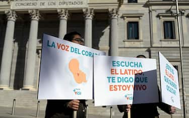 Anti-abortion protesters demonstrate with banners reading 'My heart beating means I am alive' in front of the Spanish Congress, in Madrid on February 16, 2023 as Spain prepares to approve a transgender rights law  which also provides for increased access to abortion in public hospitals. - As Spain prepares to adopt a law simplifying the process for self-identifying as transgender, other early adopters are applying the brakes over the complexities involved in this highly sensitive issue. The law is set to be passed on February 16, 2023, to approve a transgender rights bill letting anyone 16 and over change gender on their ID card. That will make it one of the few nations to allow it with a simple declaration. (Photo by OSCAR DEL POZO / AFP)