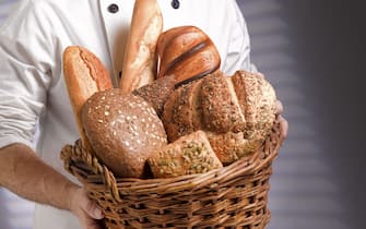 Baker carrying basket of freshly baked loaves into bakery