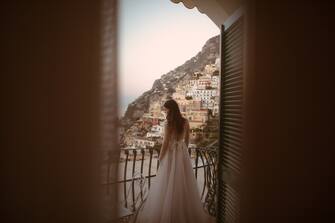 Photo of a beautiful bride standing on the terrace and enjoying in amazing view of Positano, Italy