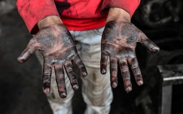 A young Syrian boy working at a machine repair shop, shows his oil-stained hands, in the town of Jandaris, in the countryside of the northwestern city of Afrin in the rebel-held part of Aleppo province, on June 11, 2022, a day before the annual World Day Against Child Labour. (Photo by Rami al SAYED / AFP) (Photo by RAMI AL SAYED/AFP via Getty Images)