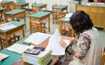Female teacher is marking exam papers in classroom
