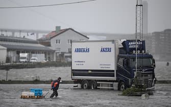 A man tears some goods towards a truck in the flooded area of the fishing port Fiskhamnen where the Gota Alv river overflowed in Gothenburg, Sweden, on August 08, 2023, after heavy rainfalls as a result of the extreme weather "Hans". Sweden's national weather agency SMHI had issued several "yellow alerts" for Monday, warning of strong winds, floods and heavy rains in multiple parts of the country as extreme weather "Hans" moved in across the country over the weekend. (Photo by Bjorn LARSSON ROSVALL / TT News Agency / AFP) / Sweden OUT (Photo by BJORN LARSSON ROSVALL/TT News Agency/AFP via Getty Images)