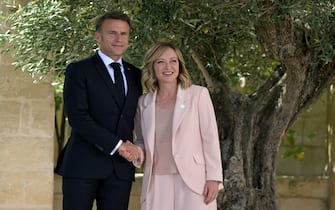 French President Emmanuel Macron is welcomed by Italy's Prime Minister Giorgia Meloni upon arrival at the Borgo Egnazia resort for the G7 Summit hosted by Italy in Apulia region, on June 13, 2024 in Savelletri. Leaders of the G7 wealthy nations gather in southern Italy this week against the backdrop of global and political turmoil, with boosting support for Ukraine top of the agenda. (Photo by Tiziana FABI / AFP)