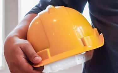 Yellow hard plastic safety helmets sit on work desks in office intended for architects and engineers to wear when entering construction sites as safety precaution because hard hats protect the head.