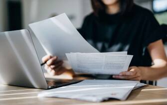 Cropped shot of young Asian woman handling personal banking and finance with laptop at home. Planning budget and calculating expenses. Managing taxes and financial bills. Wealth management. Digital banking habits. Smart banking with technology