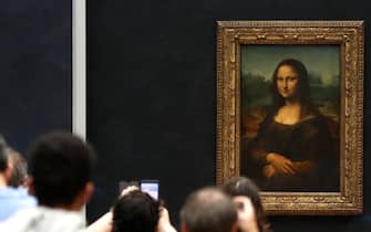Visitors wearing face masks take pictures in front of Leonardo da Vinci's masterpiece  