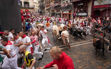 Participants run ahead of bulls during the first "encierro" (bull-run) of the San Fermin festival in Pamplona, northern Spain, on July 7, 2023. Thousands of people every year attend the week-long festival and its famous 'encierros': six bulls are released at 8:00 a.m. evey day to run from their corral to the bullring through the narrow streets of the old town over an 850 meters (yard) course while runners ahead of them try to stay close to the bulls without falling over or being gored. (Photo by CESAR MANSO / AFP) (Photo by CESAR MANSO/AFP via Getty Images)