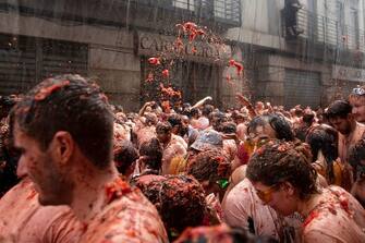 TOPSHOT - Revellers covered in tomato pulp take part in the "Tomatina" annual food battle in the Spanish eastern town of Bunol, on August 30, 2023. Around 15,000 people, gathered today in Spain's annual "Tomatina" street battle to hurl each other 120 tons of tomatoes. (Photo by Jose Miguel FERNANDEZ / AFP) (Photo by JOSE MIGUEL FERNANDEZ/AFP via Getty Images)