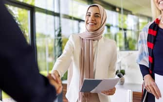 Young woman shaking hands with her new business partner after a successful deal. Business people sealing a deal with a handshake.