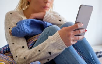 Girl using phone seated on the bed