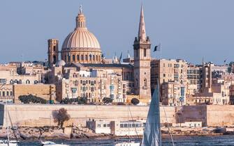 White yacht and boats in harbor of Valletta, Our Lady of Mount Carmel church and St. Paul's Anglican Pro-Cathedral on the background, Valletta, Malta