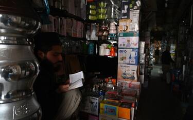 A shopkeeper recites the holy Quran while sitting at a market during a nationwide power outage in Rawalpindi on January 23, 2023. - A massive power breakdown in Pakistan on January 23 affected most of the country's more than 220 million people, including in the mega cities of Karachi and Lahore. (Photo by Aamir QURESHI / AFP) (Photo by AAMIR QURESHI/AFP via Getty Images)