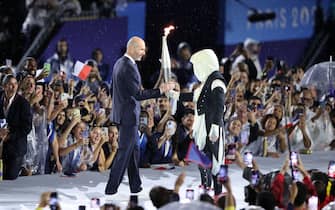 PARIS, FRANCE - JULY 26: Former footballer Zinedine Zidane carries the torch during the opening ceremony of the Olympic Games Paris 2024 on July 26, 2024 in Paris, France. (Photo by Hector Vivas/Getty Images)