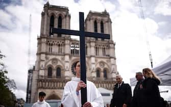 epa11249575 A priest walks with a cross as part the Good Friday procession outside the Notre Dame Cathedral in Paris, France, 29 March 2024. Christians of the Catholic and Western Christian churches around the world on 29 March commemorate Good Friday, the day when, according to the Bible, Jesus was crucified by the Romans in Jerusalem.  EPA/YOAN VALAT