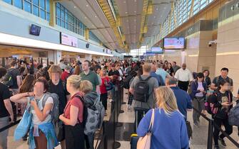 Travelers wait in line to go through security at Ronald Reagan Washington National Airport (DCA) in Arlington, Virginia, on July 23, 2023. (Photo by Daniel SLIM / AFP) (Photo by DANIEL SLIM/AFP via Getty Images)