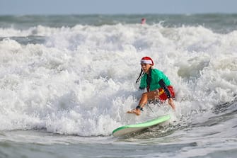 A surfer dressed as Santa rides a wave during the 15th annual "Surfing Santas" event in Cocoa Beach, Florida, on December 24, 2023. (Photo by Eva Marie UZCATEGUI / AFP) (Photo by EVA MARIE UZCATEGUI/AFP via Getty Images)