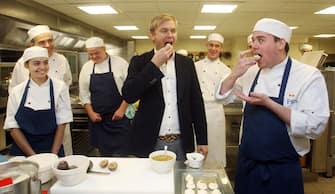 Australian chef and restaurateur Mr Bill Granger (centre) tastes a pavlova with Demi-Chef Departie Shaun Mason in the kitchens at Buckingham Palace as they make pavlova ahead of the Reception to be given in advance of the Royal Visit to Australia.   (Photo by Lewis Whyld/PA Images via Getty Images)