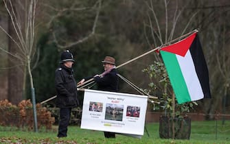 A protester speaks with a police officer as members of the British Royal Family attend their traditional Christmas Day service at St Mary Magdalene Church on the Sandringham Estate in eastern England, on December 25, 2023. (Photo by Adrian DENNIS / AFP)