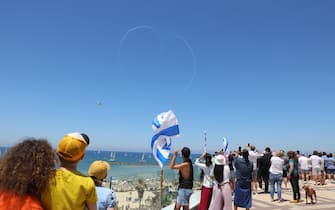epa10591936 People watch Israeli Air Force aerobatic team performing during Independence Day air show above the beaches of Tel Aviv, Israel, 26 April 2023. Israel is celebrating the 75th Independence Day.  EPA/ABIR SULTAN