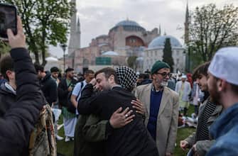 epa10583409 Muslim faithful hug after taking part in Eid al-Fitr prayers in front of the Hagia Sophia Grand Mosque in Istanbul, Turkey, 21 April 2023. Muslims around the world celebrate Eid al-Fitr, the three-day festival marking the end of Ramadan that is one of the two major holidays in the Islamic calendar.  EPA/ERDEM SAHIN