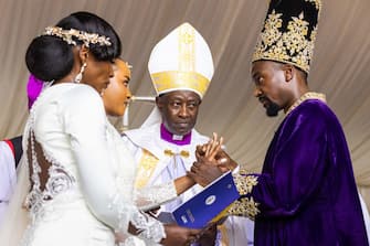 The Kyabazinga (King) of the Busoga Kingdom William Gabula Nadiope IV (R) puts a ceremonial ring on the finger of the Inhebantu (Queen) Jovia Mutesi during their royal wedding at the Christ's Cathedral Bugembe in Jinja on November 18, 2023. (Photo by BADRU KATUMBA / AFP) (Photo by BADRU KATUMBA/AFP via Getty Images)