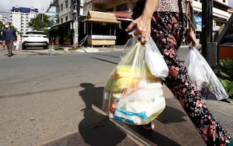 epa09409080 A woman carries plastic bags of meat and vegetable on a street in Phnom Penh, Cambodia, 11 August 2021. According to Cambodian Ministry of Environment spokesman Neth Pheaktra, people in Phnom Penh generated 2,700 to 3,000 tons of garbage every day, of which more than 20 percent is plastic waste as COVID-19 encouraged people to use more plastic as preventive materials and packaging for food.  EPA/MAK REMISSA