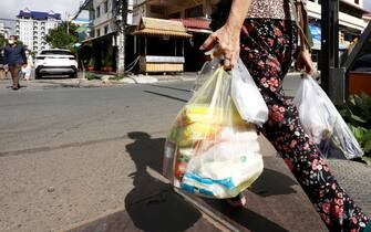 epa09409080 A woman carries plastic bags of meat and vegetable on a street in Phnom Penh, Cambodia, 11 August 2021. According to Cambodian Ministry of Environment spokesman Neth Pheaktra, people in Phnom Penh generated 2,700 to 3,000 tons of garbage every day, of which more than 20 percent is plastic waste as COVID-19 encouraged people to use more plastic as preventive materials and packaging for food.  EPA/MAK REMISSA