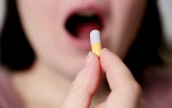 Woman takes a pill, girl putting capsule in open mouth. Sick female taking medicines, concept of antibiotic, vitamin, coronavirus prevention