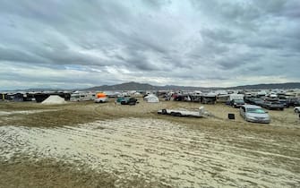 Camps are set on a muddy desert plain on September 2, 2023, after heavy rains turned the annual Burning Man festival site in Nevada's Black Rock desert into a mud pit. Tens of thousands of drenched festivalgoers were stranded on September 3, 2023, in deep, sticky mud in the Nevada desert after torrential rain turned the annual Burning Man gathering into a quagmire. All events at the counterculture festival, which drew some 70,000 people, were canceled after rain tore down structures for dance parties, art installations and other eclectic entertainment. (Photo by Julie JAMMOT / AFP) (Photo by JULIE JAMMOT/AFP via Getty Images)