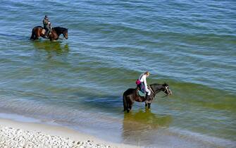 ODESA, UKRAINE - JANUARY 2, 2023 - People ride horses along the coast of the Black Sea in winter as the city experiences the record temperatures for January in 100 years at 16 degrees Celcius (61 degrees Fahrenheit), Odesa, southern Ukraine. (Photo credit should read Yulii Zozulia / Ukrinform/Future Publishing via Getty Images)