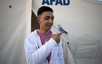 KAHRAMANMARAS, TURKIYE - FEBRUARY 24: Omer Yilmaz, an earthquake survivor lives the tent city established in Vali Saim Cotur Stadium and around with his parakeet named "Ãiko" after 7.7 and 7.6 magnitude earthquakes hit multiple provinces of Turkiye including Kahramanmaras on February 24, 2023. Some survivors of earthquakes in Kahramanmaras live together in a tent city with their animals, such as fish, birds, partridges, cats and dogs, which they rescued while leaving their homes. Established by the Sakarya 7th Commando Brigade Command, the tent city hosts nearly 3,500 earthquake victims as well as dozens of pets. (Photo by Fatih Kurt/Anadolu Agency via Getty Images)