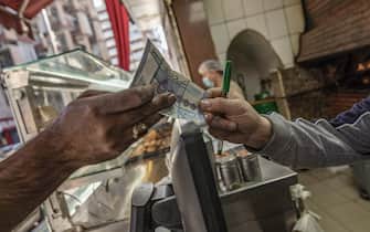 A customer hands over a Lebanese pound banknote in a bakery on Hamra Street in Beirut, Lebanon, on Tuesday, April 13, 2021. Lebanon's annual inflation rate reached a record high and food prices soared by around 400% in December, highlighting the dramatic impact on consumers and businesses of the country's worst financial crisis in decades. Photographer: Francesca Volpi/Bloomberg