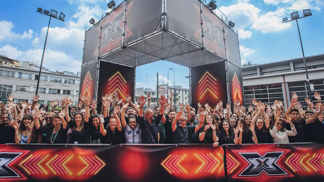 Una folla felice di persone aspetta di entrare come pubblico a X Factor 