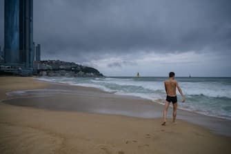 A swimmer walks towards the water during swells brought by the approaching typhoon Maysak on Haeundae beach in Busan on September 2, 2020. - Flights were grounded in South Korea and storm warnings issued on both sides of the Korean peninsula as a typhoon forecast to be one of the most powerful in years made its approach. (Photo by Ed JONES / AFP) (Photo by ED JONES/AFP via Getty Images)