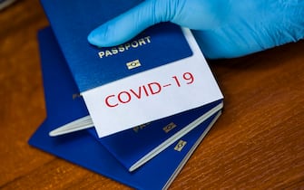 Man holding a passport with COVID-19 sign stamped onto a white paper, immunity passport or risk-free certificate concept, recovered Coronavirus COVID19 patients being issued proof of convalescence