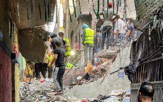 First responders and locals search for survivors in the rubble at the scene of a building collapse in the Hadayiq al-Qubba district of Cairo on July 17, 2023. (Photo by Ahmed HASAN / AFP) (Photo by AHMED HASAN/AFP via Getty Images)