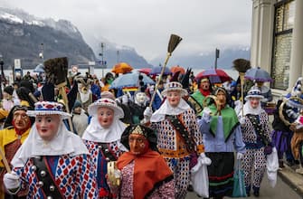 epa11064154 So-called Nuessler, men or boys in traditional costumes and masks that are derived from those worn by the characters in the Venetian Commedia dell'Arte, parade through the streets of Brunnen, Switzerland, 08 January 2024, marking the opening of the carnival season.  EPA/URS FLUEELER