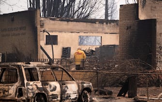 Un uomo del CalFire esamina i resti di un ufficio postale bruciato a Greenville
