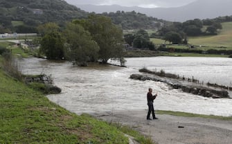 A man takes pictures with his phone after the Gravona river flooded the area due to Storm Domingos on the French Mediterranean island of Corsica in  in Bastelicaccia on November 5, 2023. Two days after Ciaran, a new storm named Domingos swept across France, causing power cuts and keeping 12 departments on orange alert across the country. (Photo by Pascal POCHARD-CASABIANCA / AFP) (Photo by PASCAL POCHARD-CASABIANCA/AFP via Getty Images)