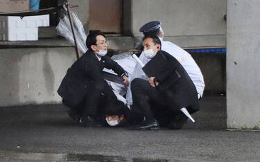 A man (bottom) is arrested after throwing what appeared to be a smoke bomb in Wakayama on April 15, 2023. - Japanese Prime Minister Fumio Kishida was evacuated from a port in Wakayama after a blast was heard, but he was unharmed in the incident, local media reported on April 15. (Photo by JIJI Press / AFP) / Japan OUT (Photo by STR/JIJI Press/AFP via Getty Images)