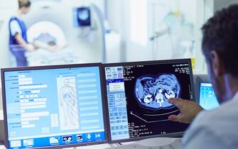 Male doctor running CT scan from control room at hospital