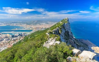 Gibraltar Rock view from above, on the left Gibraltar town and bay, La Linea town in Spain at the far end, Mediterranean Sea on the right.